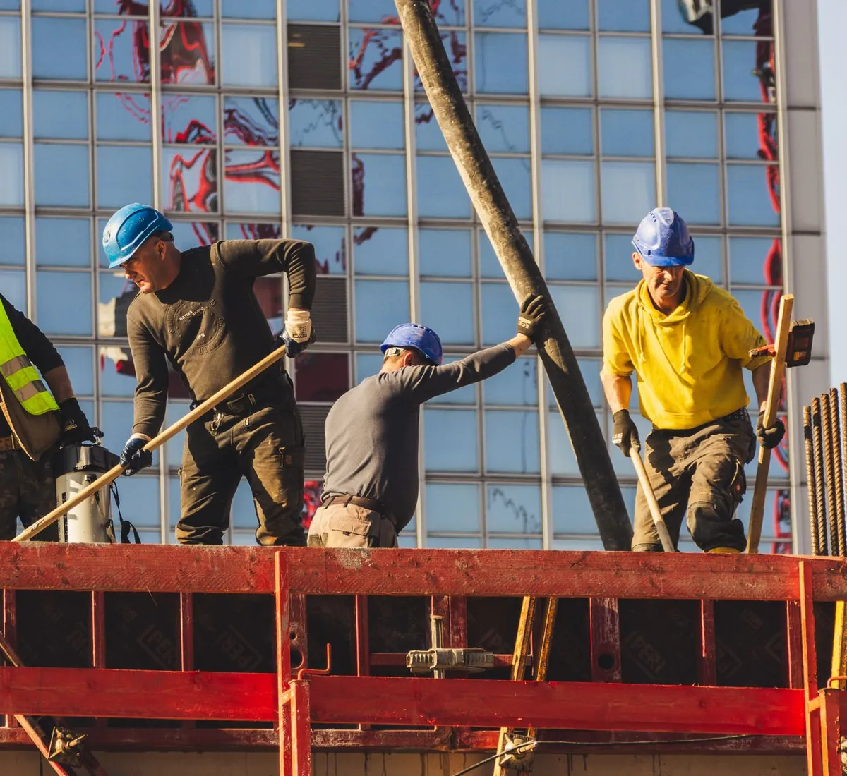 Site workers in hard hats fixing steel on a high-rise building