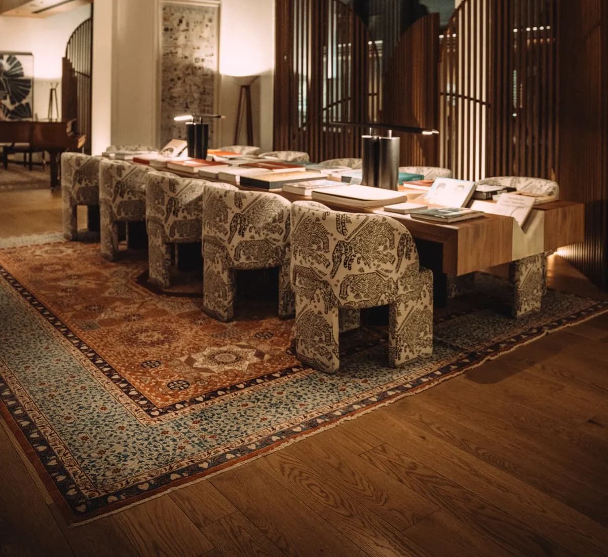 Warmly lit luxury hotel lounge with upholstered chairs around a long table